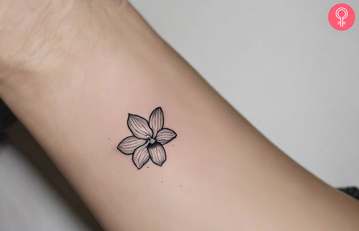 A woman with a minimalist orchid tattoo on her wrist