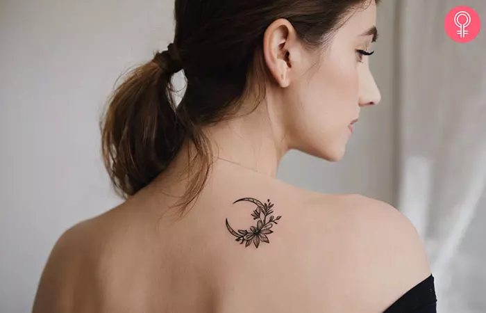 A woman with a moon tattoo intertwined with flowers on her back