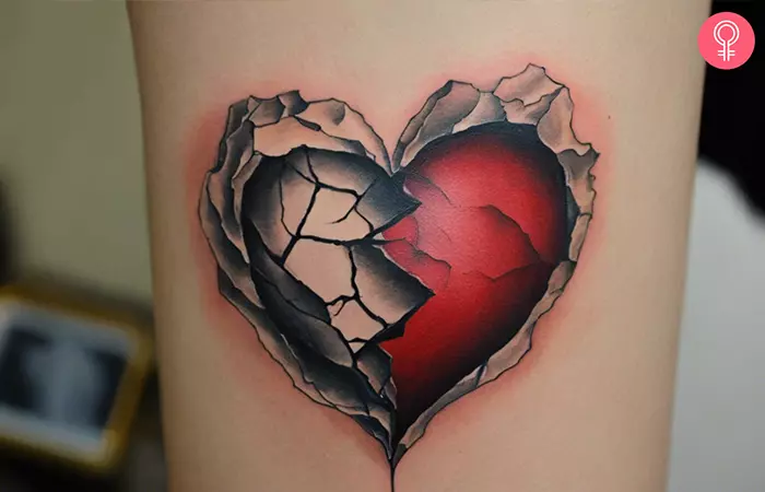 A woman with a realistic broken heart tattoo on her upper arm