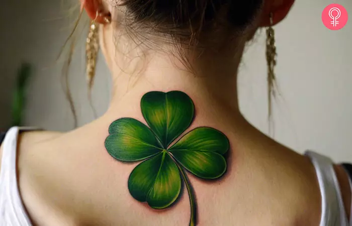 A woman with a realistic four-leaf clover tattoo on her upper back