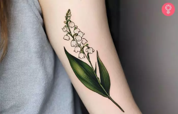 A woman with a simple lily of the valley tattoo on her arm