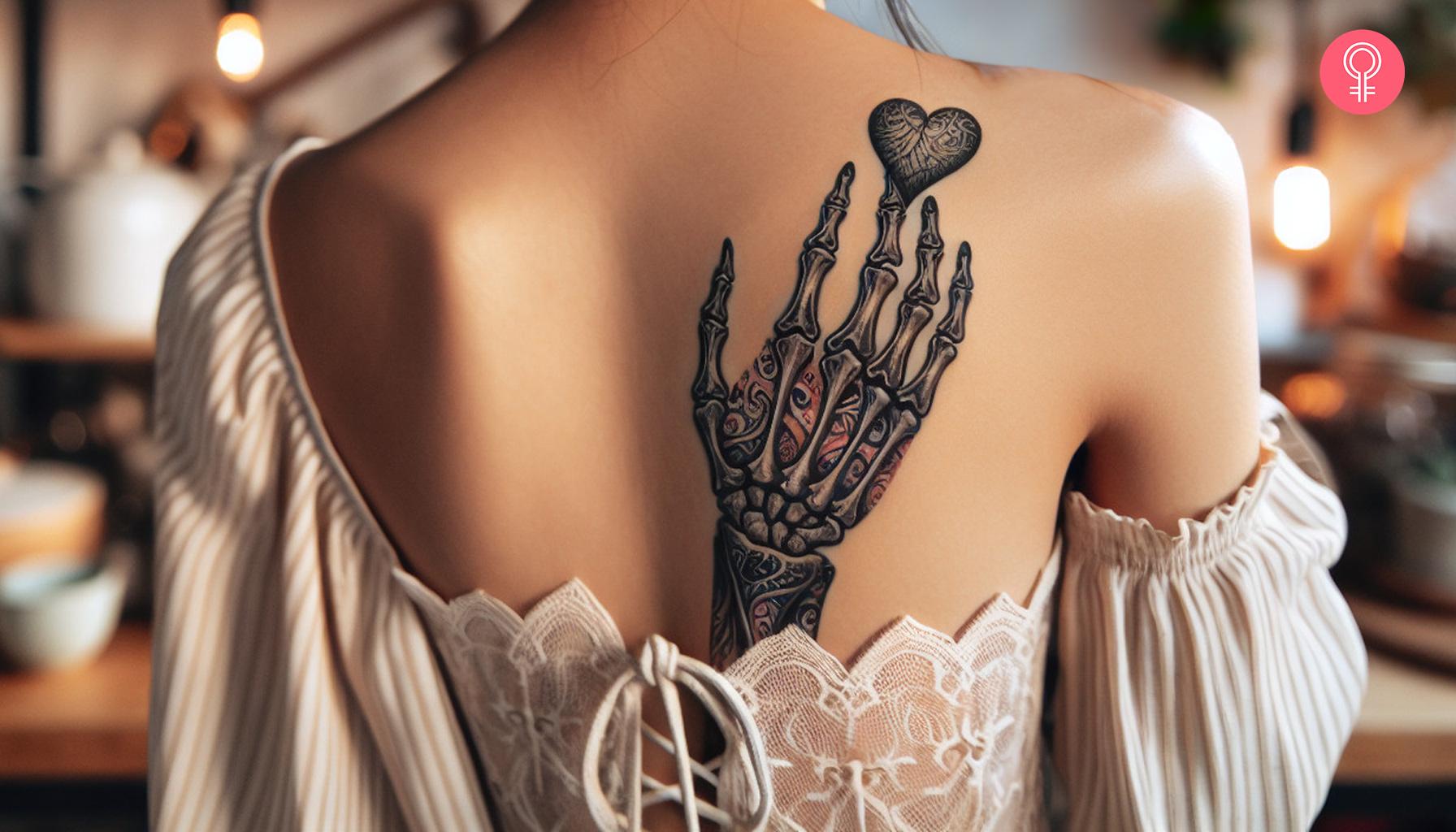 A woman with a skeleton hand heart tattoo on her back