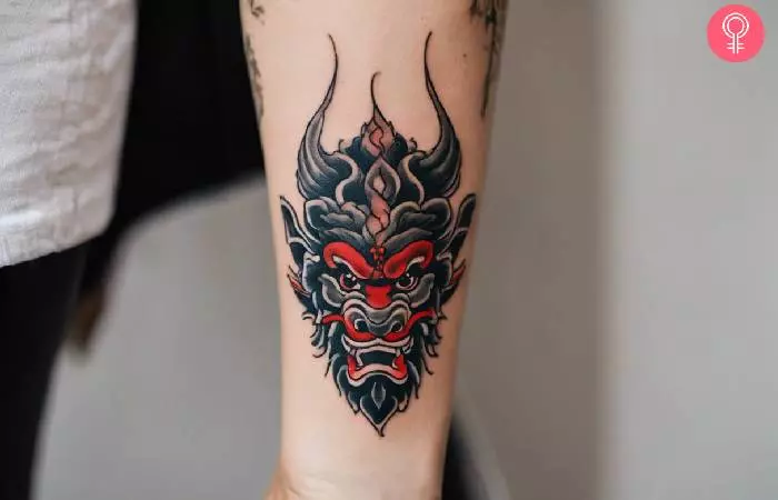 A woman with a small Tebori oni mask tattoo on forearm