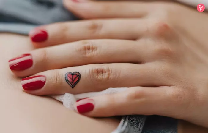 A woman with a small broken heart tattoo on her ring finger