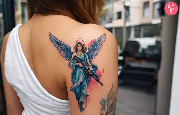 A woman with a tattoo of an angel carrying an AK-47 on her upper arm