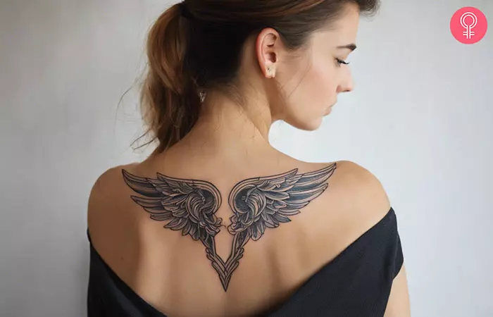 A woman with a tattoo of the wings of Valkyrie across her upper back shoulder