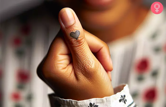 A woman with a tiny heart thumb tattoo