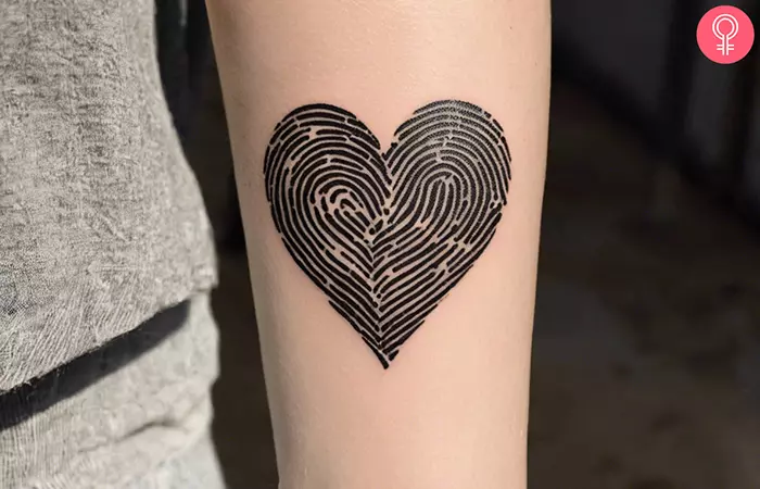 A woman with a two fingerprint heart tattoo on her forearm