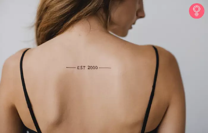 A woman with an Est 2000 tattoo on her upper back