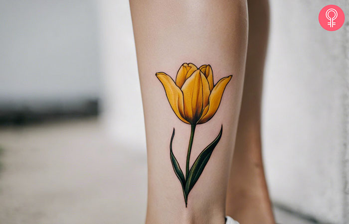 A yellow tulip tattoo on the leg