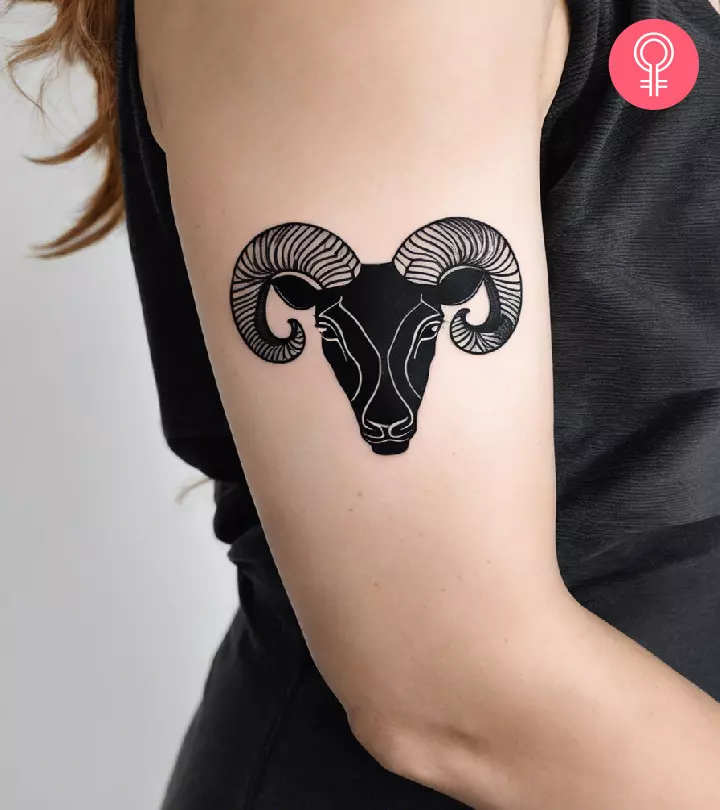 An Aries tattoo on the upper arm of a woman