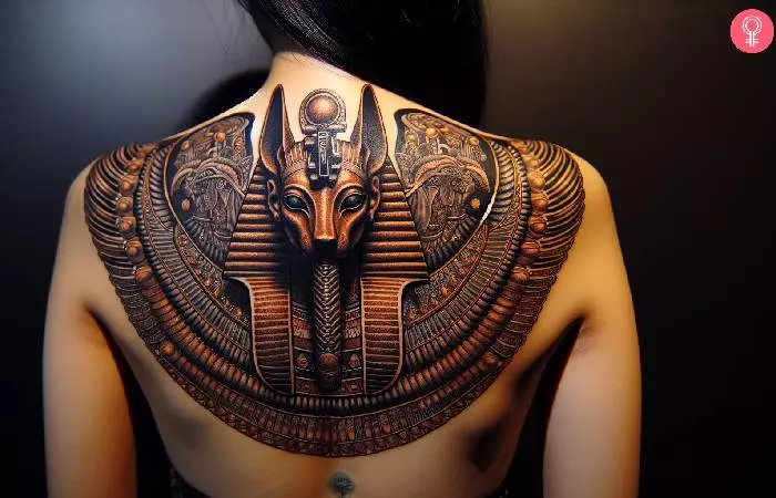An intricate ornamental tattoo of the bust of Anubis on a woman’s back