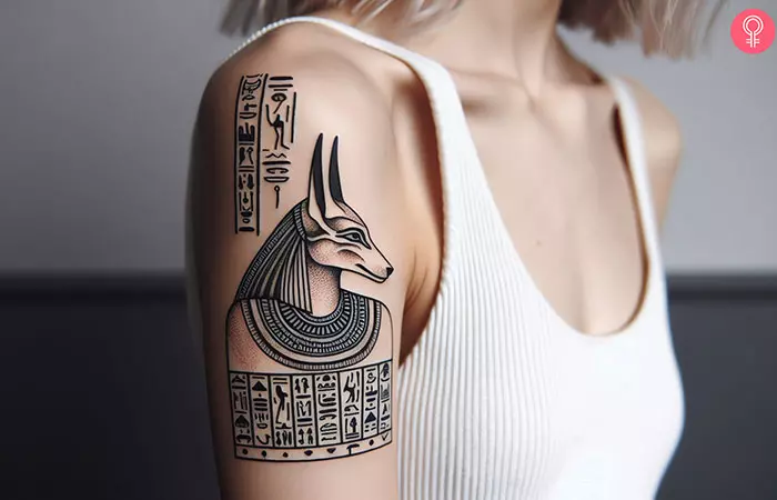 An upper arm tattoo of Anubis and hieroglyphics