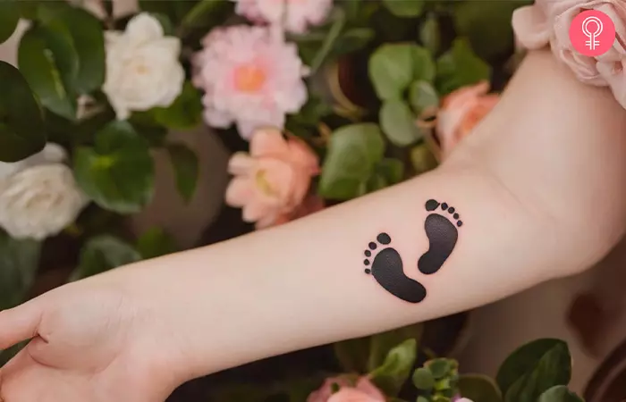 Baby footprint tattoos on a woman’s arm