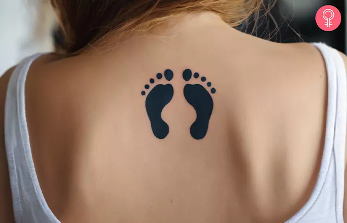 Baby footprints tattoo on a woman’s upper back