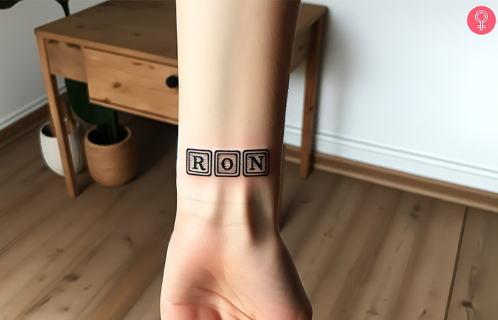 A wrist tattoo of baby name in blocks