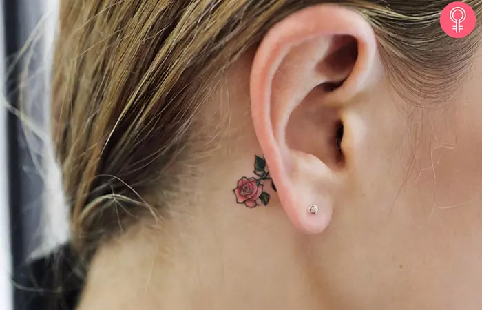 A small pink rose tattoo behind the ear
