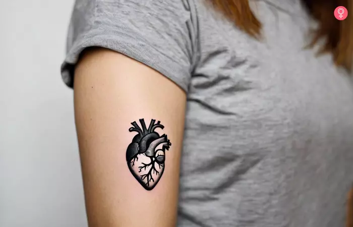 Woman with a black anatomical heart tattoo on the arm