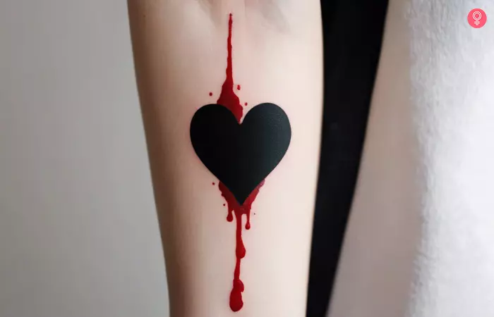 Woman with a black bleeding heart tattoo on the forearm