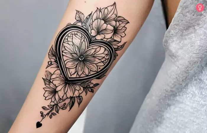 Woman with a black heart and flowers tattoo on the forearm