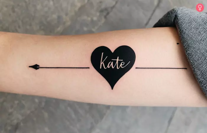 Woman with a black heart tattoo that contains the name Kate