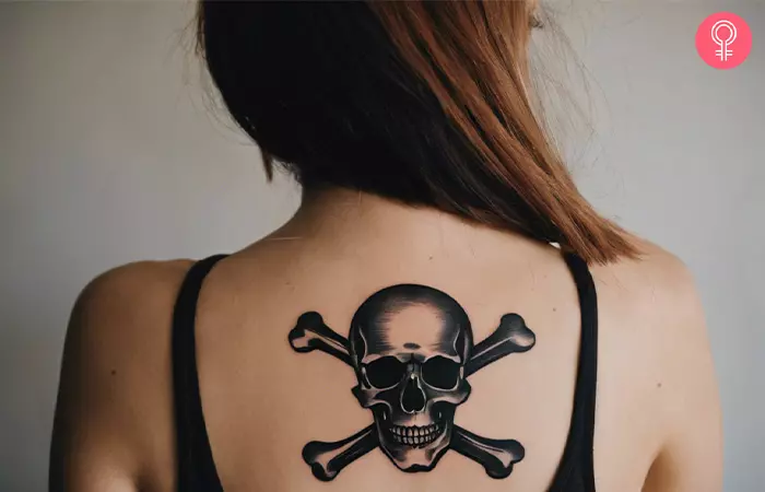 A woman with a black skull and crossbones tattoo on her back
