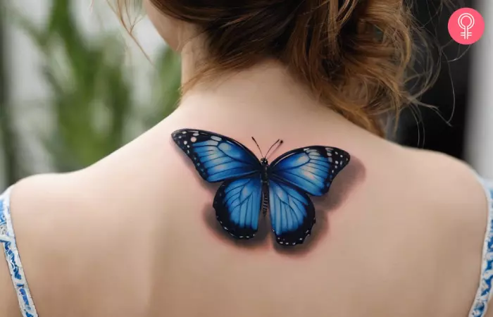 Blue 3D butterfly tattoo on a woman’s back