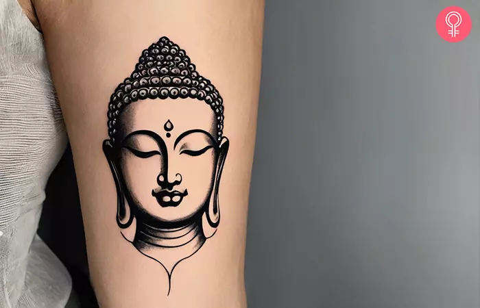 Buddha tattoo on the upper arm of a woman
