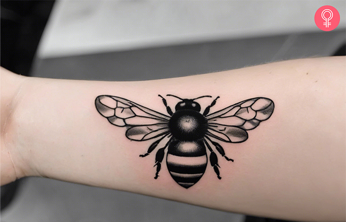 A black and white bumble bee tattoo on the forearm