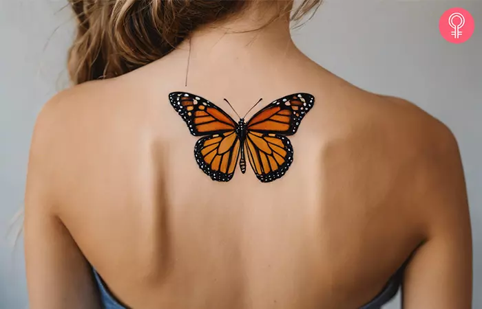 A woman showcasing a monarch butterfly tattoo on her upper back