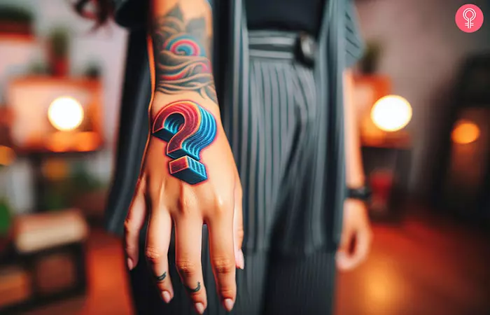 A colorful 3D question mark tattoo on the hand of a woman