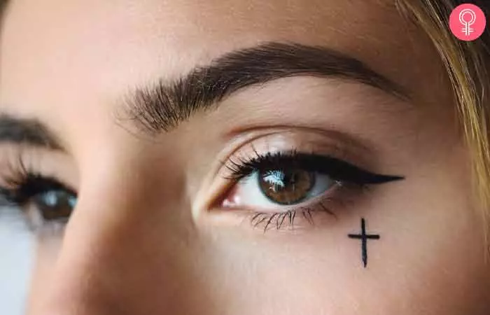 Cross tattoo under the eye