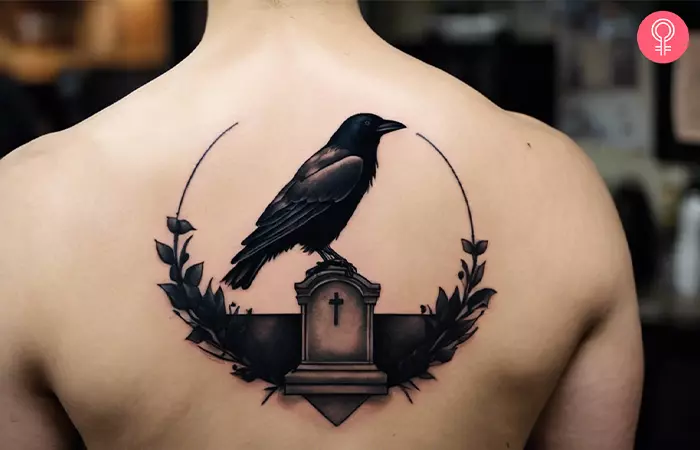 A crow sitting on a tombstone tattoo on the back
