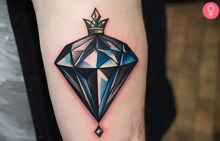 A crown and diamond tattoo on the upper arm of a man