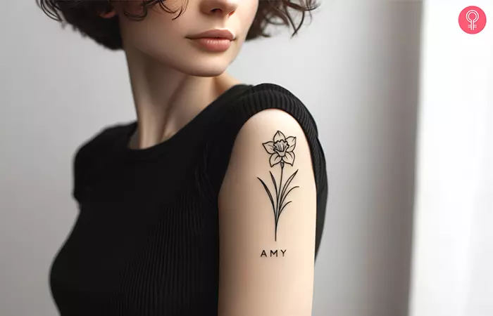 A daffodil tattoo with a name on the upper arm
