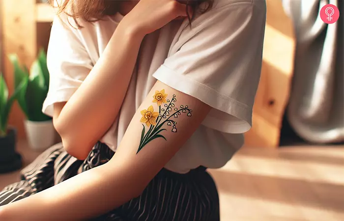A daffodil and lily of the valley tattoo on the upper arm