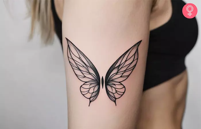 A woman with a fairy wings tattoo on the upper arm