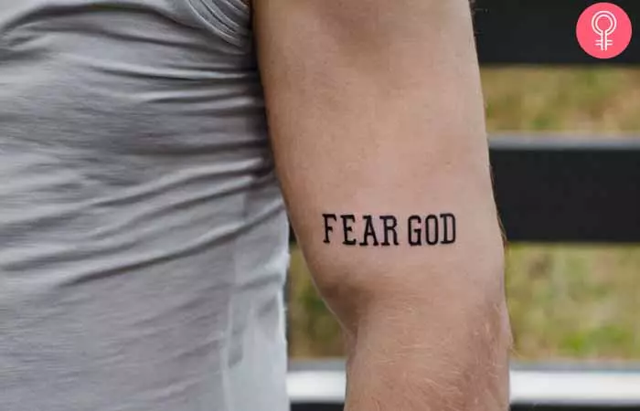 A man with a fear god tattoo on his bicep 