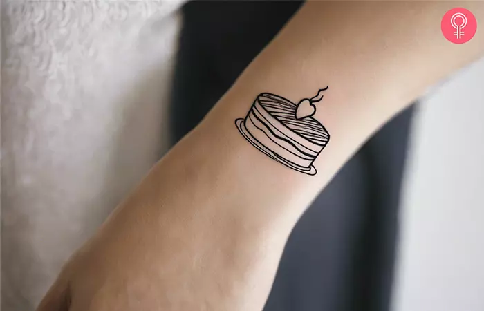 Fine line cake tattoo on the wrist