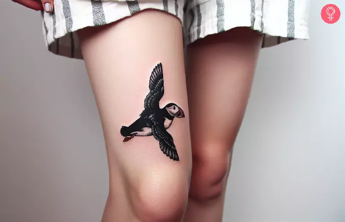 Flying puffin tattoo on a woman’s thigh