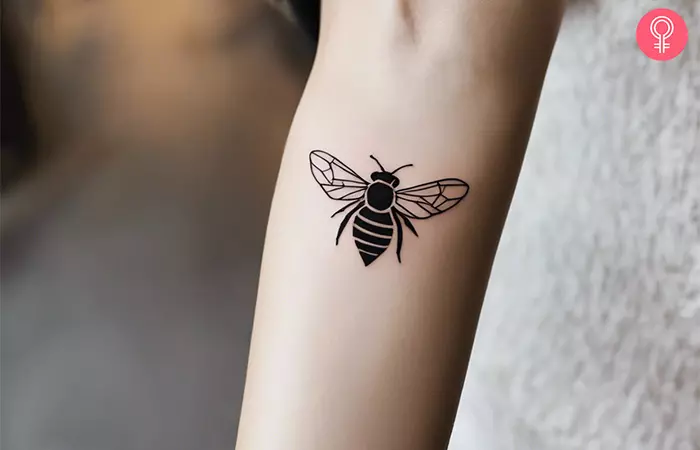A woman with a geometric bee tattoo on her arm