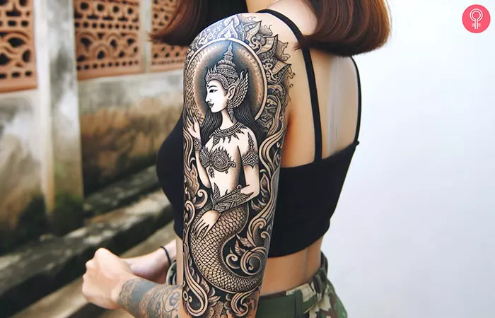 Woman with goddess mermaid tattoo on her outer arm