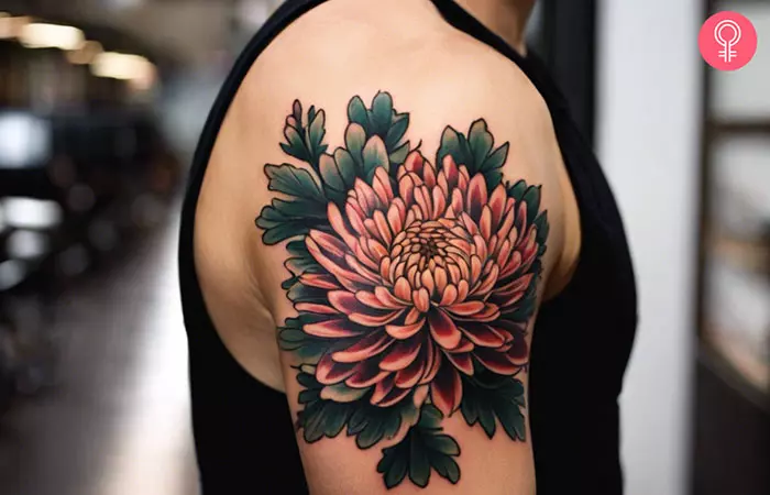 A Japanese chrysanthemum tattoo with dark leaves on a man’s bicep