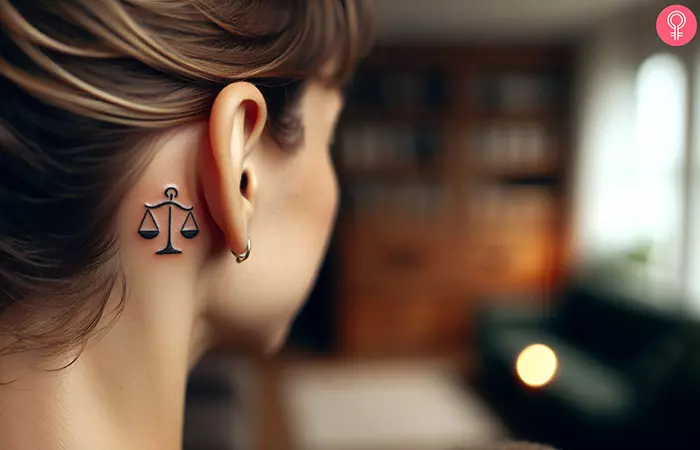 A woman with a Libra zodiac sign tattoo behind the ear
