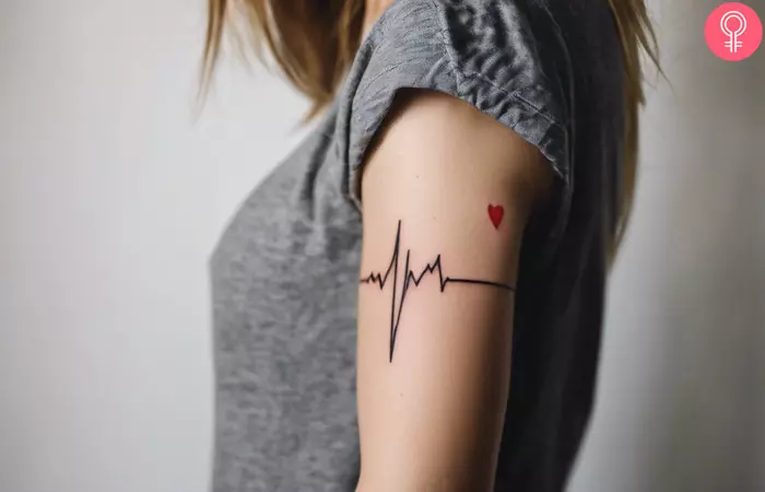 A woman wearing a love heartbeat tattoo on her upper arm.