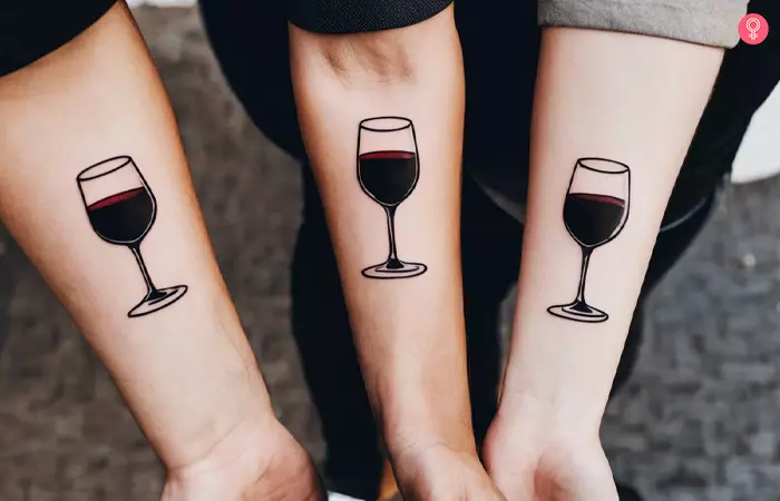 Matching wine glass tattoos on lower arms