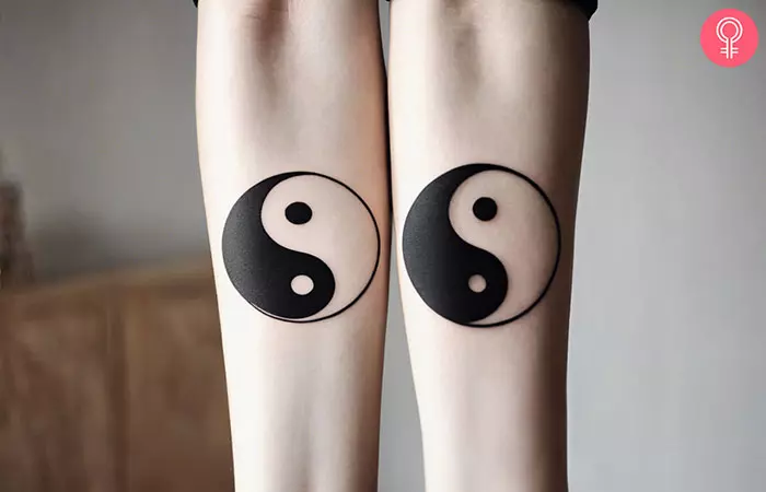 Matching yin yang tattoos on the forearms