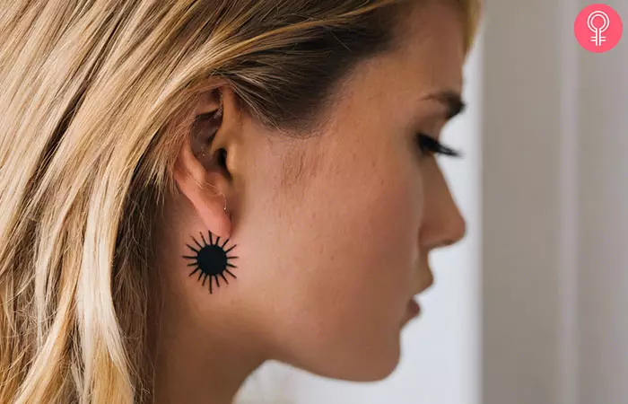 A black behind the ear sun tattoo on a woman.
