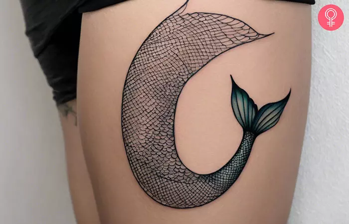 Woman with mermaid tail tattoo on her thigh