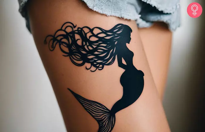 Woman with mermaid tattoo on her thigh
